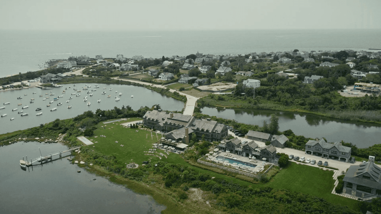 Sailboats moored off a shingled clubhouse and lawn on the Rhode Island coast, seen from the air