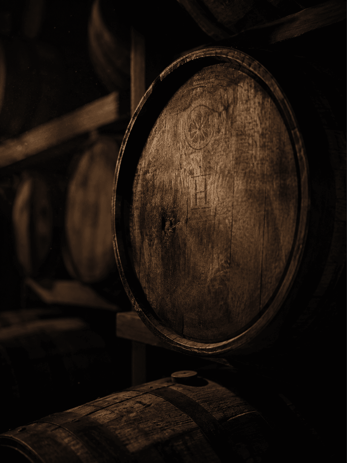 An oak cask resting on its side in a dim rickhouse